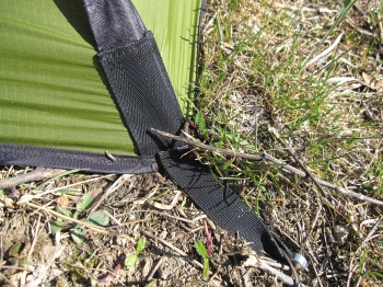 Ici tension du double toit à l'aide d'une boucle de sangle sur sardine