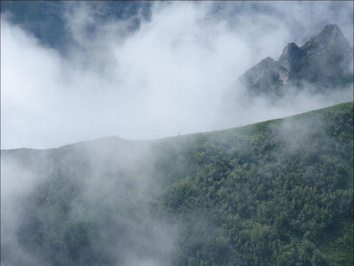 Une personne se laisse apercevoir dans le brume, sur la crête juste en face.