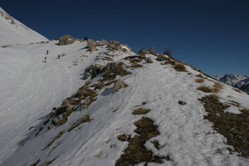 Vers 2000 m d'altitude, je suis au même niveau qu'un groupe de trois skieurs de randonnée. La neige est rare sur la crête exposée au vent.