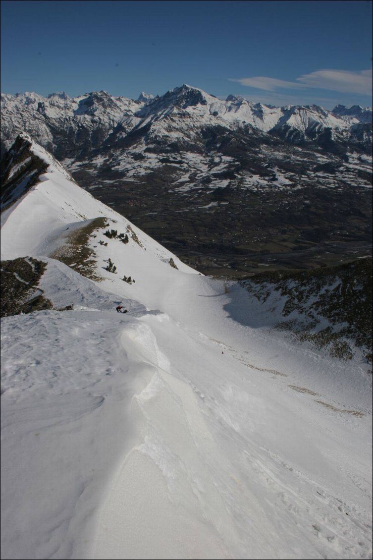 L'arête sommitale du Pic de Gleize est ourlée d'une petite corniche. Tout en bas, le bocage du Champsaur est déneigé.