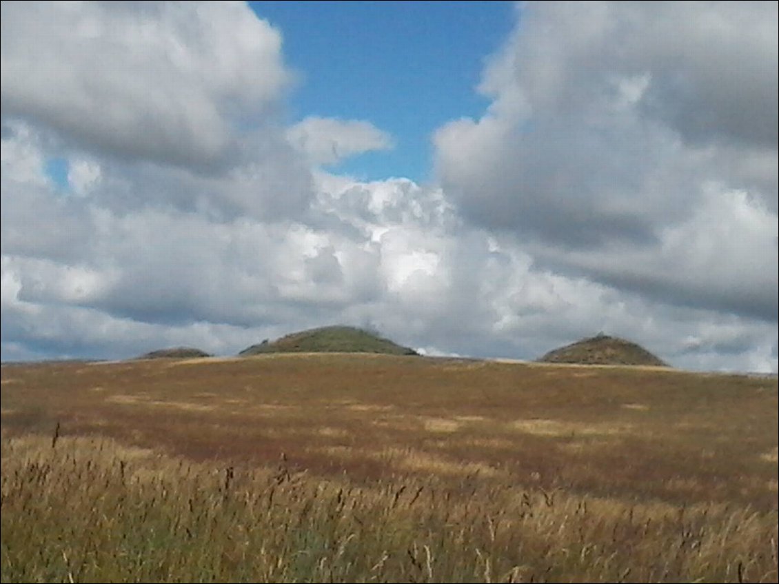 Trois tumulus de l'âge du bronze dans un champ.