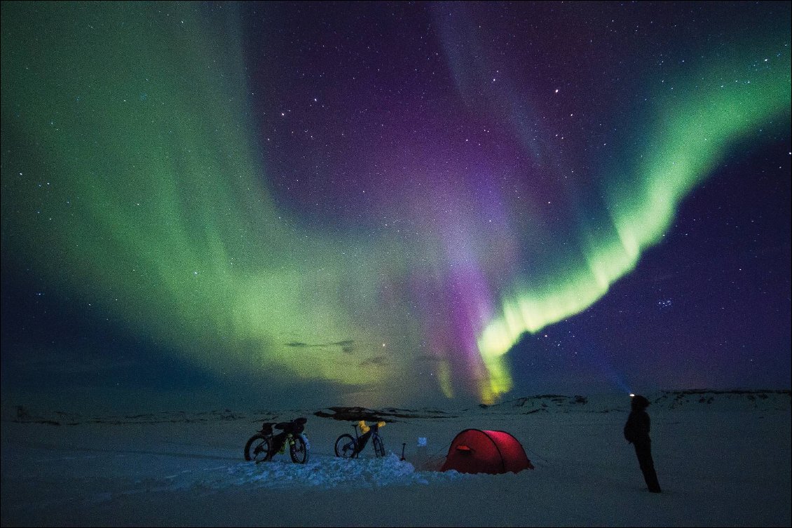 Islande : Fat-bike-packing, les highlands enneigés à VTT
En avril, le crépuscule est à 21h ; il fallait donc attendre (ou se relever) minuit environ si nous voulions voir des aurores boréales. Mais le spectacle en vaut la peine ! Nous restions aussi longtemps que nous pouvions dans le froid nocturne, juste pour observer les lumières célestes qui allument la neige en vert et violet. Plus tard, couchés dans la tente, nous pouvions encore voir les lumières à travers le tissu.
Photos : Oliver et Annie Lloyd-Evans