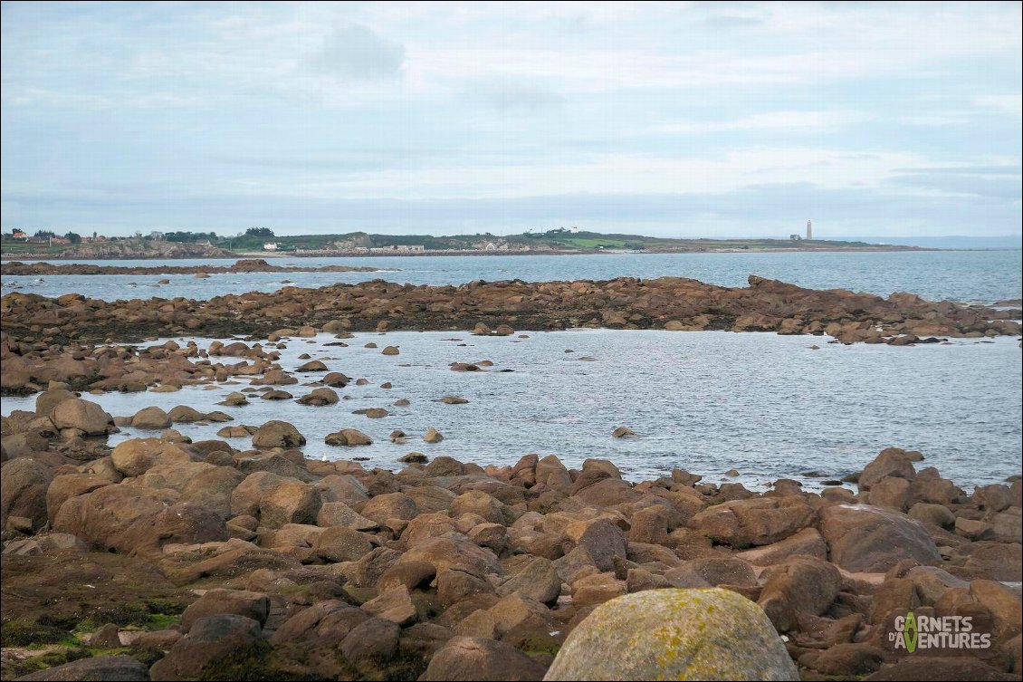 Le granit s'impose doucement. Au loin, le phare du Cap Lévi.