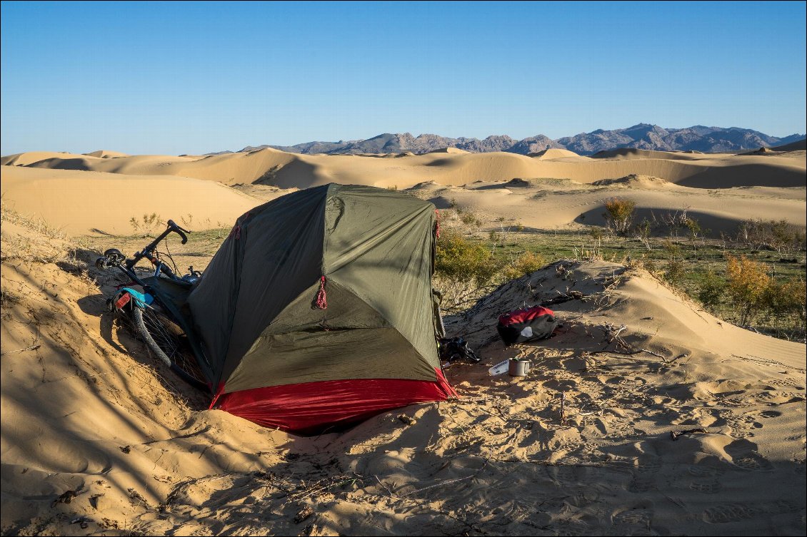 12# Lionel POURCHIER.
Mini-Gobi, Traversée de la Mongolie à vélo.
Je sors de la route au hasard et rencontre vite une surface de sable qui me stoppe. C’est le prix à payer pour camper dans les dunes ; pousser mon vélo de 40kg dans le sable fin pendant plus d’une heure pour couvrir une distance modeste de 500 mètres. J’ai trouvé ce que je recherchais, des dunes de plusieurs mètres de haut à perte de vue, et la solitude fictive d’une nuit dans le désert.