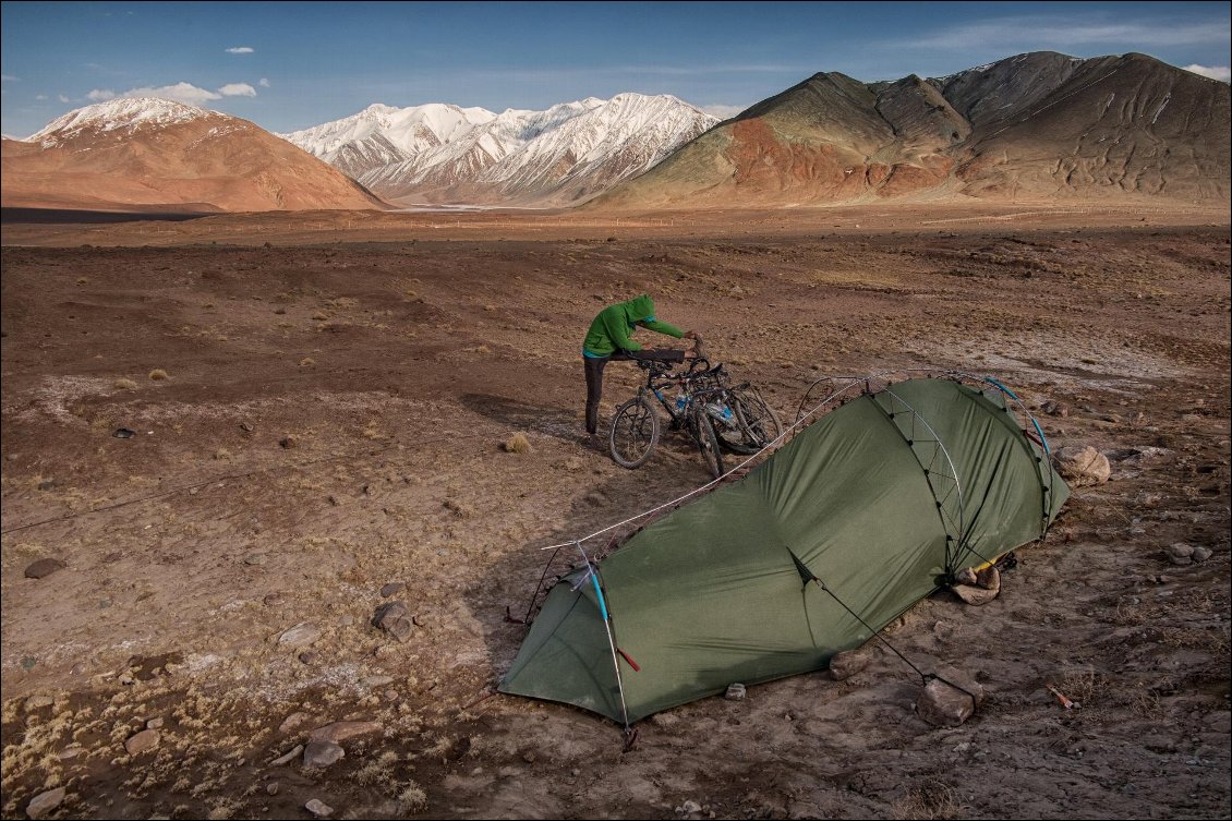 37# Yann HAMON.
Tadjikistan, fin avril 2016. Route du Pamir (M41) entre la frontière tadjike / kirghize et le lac Karakul.
Paysage lunaire où on a décidé de planter la tente. Aurélie fait des étirements après que nous avons fait notre premier col sur cette route mythique : le Kyzyl Art Pass.