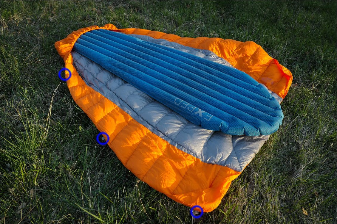 L'intérieur du quilt, avec un matelas en 183cm de long et 51cm de large : on remarque par ailleurs la compartimentage complexe pour garder le duvet en place.
Entourées en bleu, les 3 boucles présentes sur un côté permettent de créer son propre système d'attache, selon le matelas qu'on a, et selon ses préférences.