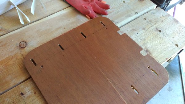 La plaque de bois est creusée des fentes qui serviront a fixer le siège.