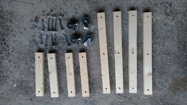 L'ensemble des pièces. Une dizaine de vis-écrous-rondelles, 2 roulettes fixes et deux tournantes pour l'avant, 8 morceaux de bois + une barre en alu non visible (voir ci-dessous). L'entraxe des trous est fixe (ici, une vingtaine de centimètre). Les petites barres mesurent donc 20+2x2 = 24 cm et les grandes barres 20x2+2x2=44cm. Il est donc très facile de faire une charriot de la taille qu'on veux : pas de calculs compliqués.