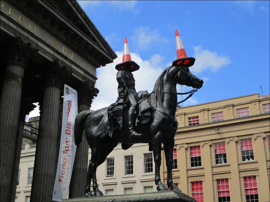 Cékoidonc ?
C'est la statue du duc de Wellington coiffé de son sempiternel "chapeau" (depuis plus de trente ans). Ce couffre-chef est apparu lors d'une soirée de beuverie et est maintenant la marque de Glasgow et de son sens de l'humour particulier. Un peu jaloux, le fier destrier a finalement reçu le même.