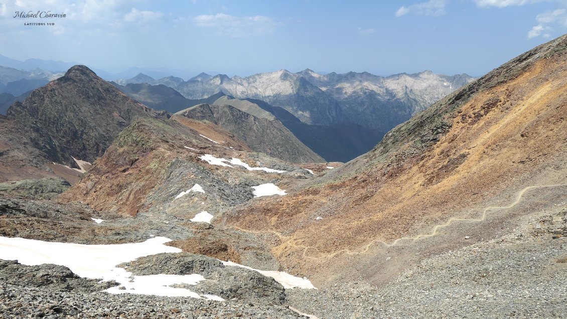 Depuis le col de Riufret, entre le Montcalm et le Pic d'Estats. Les 3000 du secteurs (Montcalm, Estats et et Pic du Port de Sullo) forment la ligne de crête d'un cirque sauvage, minéral, dans les tons brun-orangé. Ca a de la gueule, et le contraste que génère ces couleurs avec l'étonnant relief en dalles claires du massif de Bassiès, de l'autre côté du vallon de l'Artigue, n'y ait pas étranger.