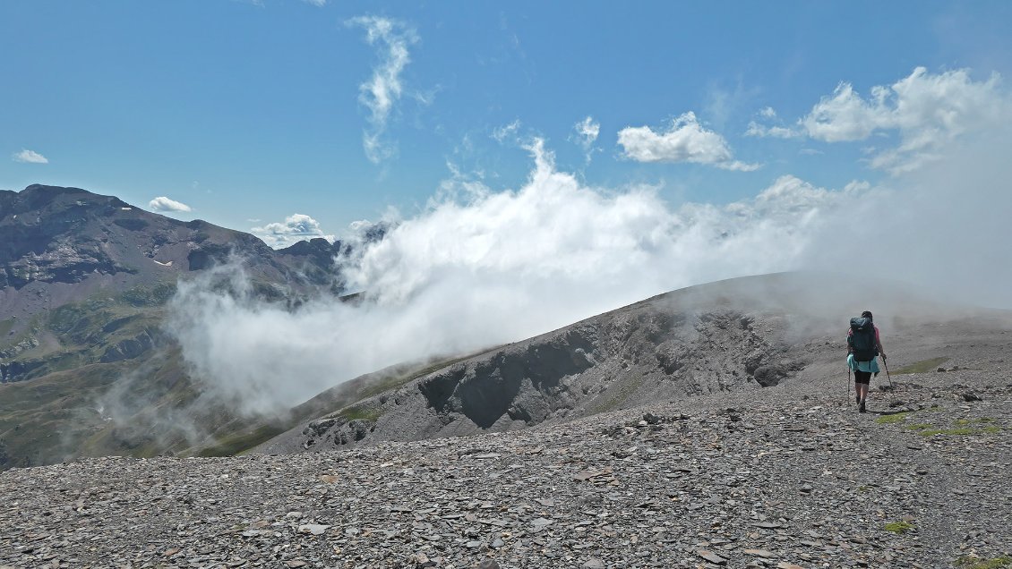 J29. Cheminement sur la crête frontière vers le Tuco de Mommour. Côté français, des nuages remontent de la profonde vallée du Rioumajou.