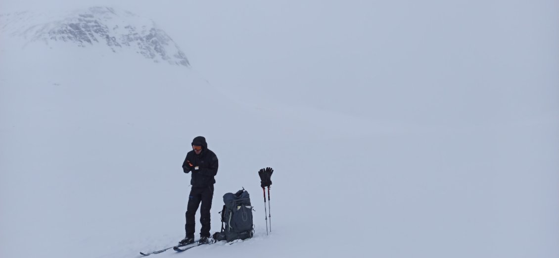 J6. La pause déjeuner se fait debout car le temps ne me permet pas de m'arrêter de façon prolongée. Je tourne le dos au vent, derrière moi c'est donc l'endroit où je vais. Ciel et neige commencent à se confondre.