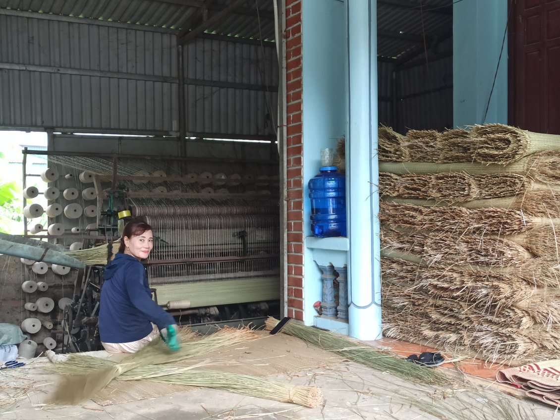 J17. Cette dame m'a accueilli à l'entrée de sa maison. Elle y transforme les herbes séchées en produit fini pour confectionner des paniers et autre objets (sur la droite de la photo).