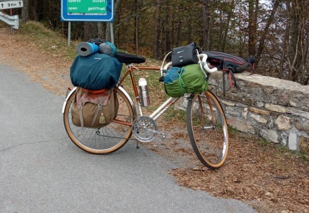 À l'avant : un sac de couchage et l'électronique. À l'arrière : deux sacoches + un sac a dos et un matelas de sol.