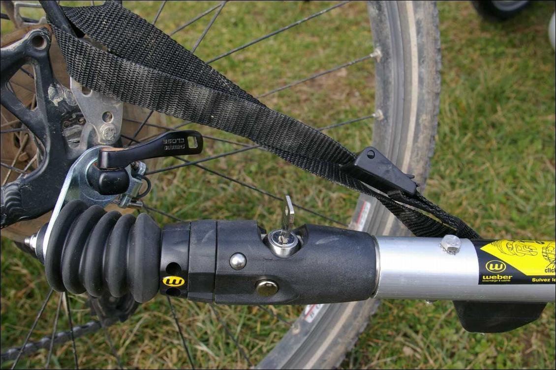 Fixation au vélo : système Weber articulé et sécurisé avec un câble en acier, facile à mettre en place mais d'expérience (sur remorque Weber Monoporter) fragile