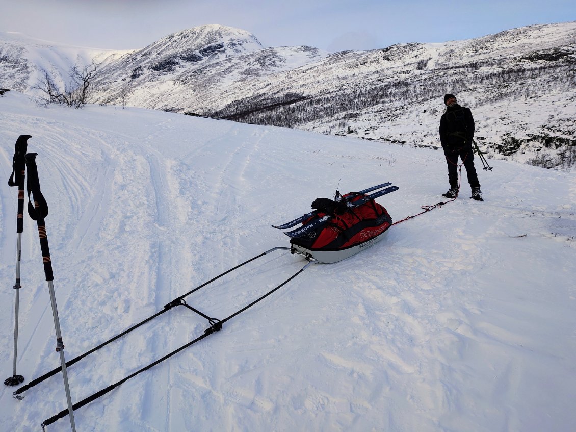 J10. Pour passer une descente un peu raide, j'ai retiré mes skis. Je retiens la pulka en marchant à l'avant. Gilles la retient à l'arrière avec une corde.