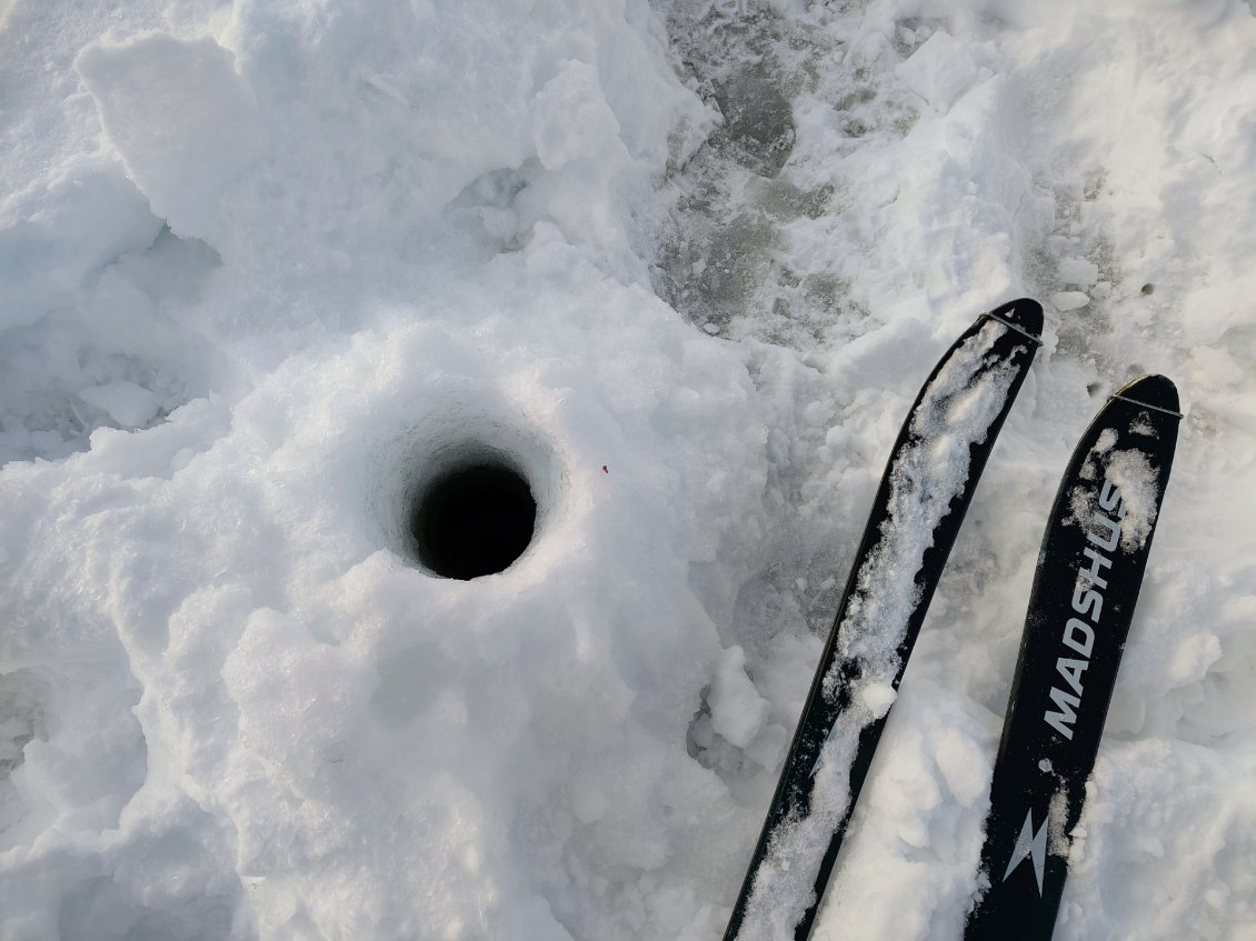 J12. Sur un lac gelé, trou de tarrière dans la glace, pour la pêche. Il y en avait plusieurs dans le même secteur.