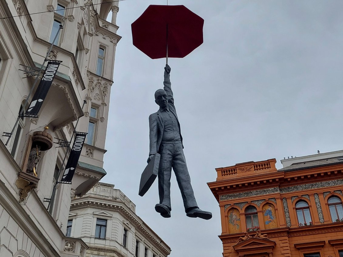 Dans la ville nouvelle, un Mary Poppins au masculin semblant voler grâce à son parapluie, sculpture de David Cerny