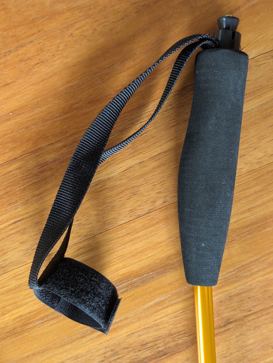 Dragonne non réglable avec velcro (cousu dessus) pour maintenir le bâton replié.