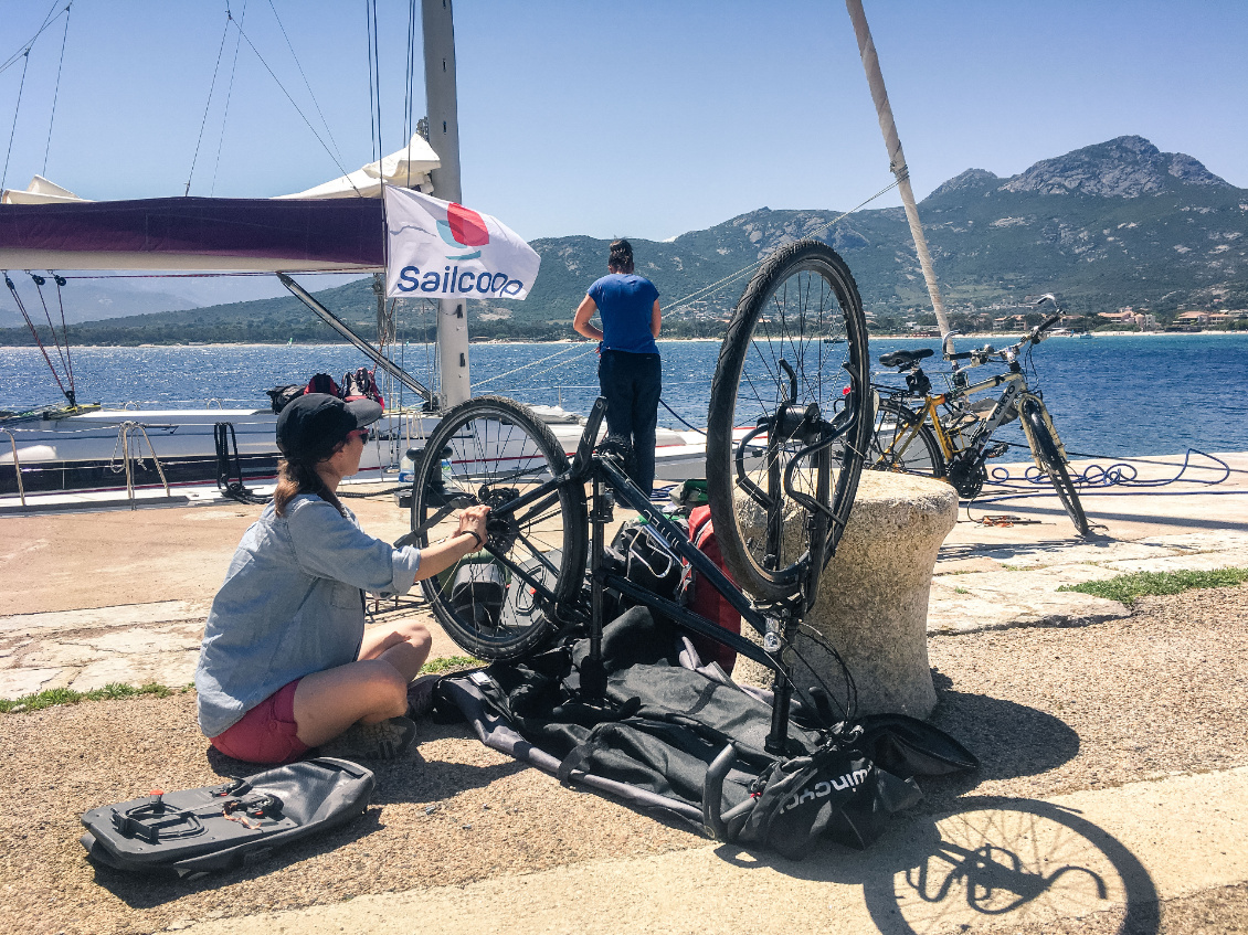 Sailcoop. Remontage minutieux des vélos à Calvi (Corse) après une incroyable traversée à
la voile. Photo : Loïc Blanchet-Mazuel